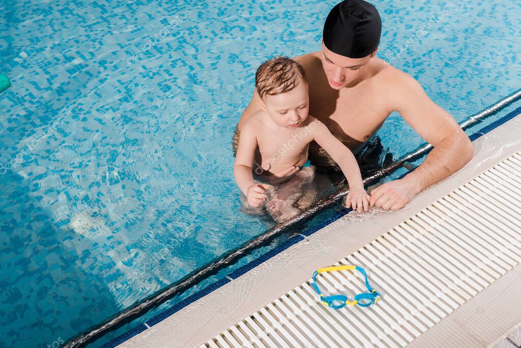Schwimmtrainer unterstützt eine erwachsene Teilnehmerin im Wasser