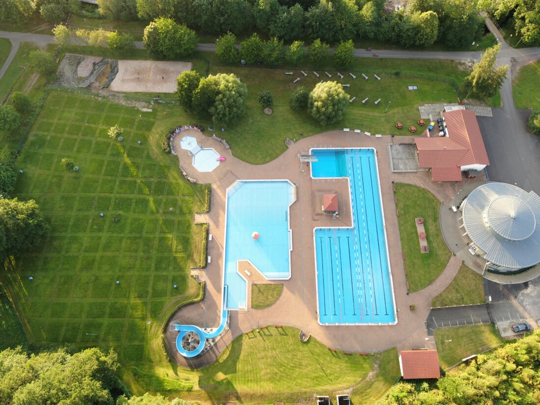 Liegewiese mit Bäumen und Badetüchern im Freibad